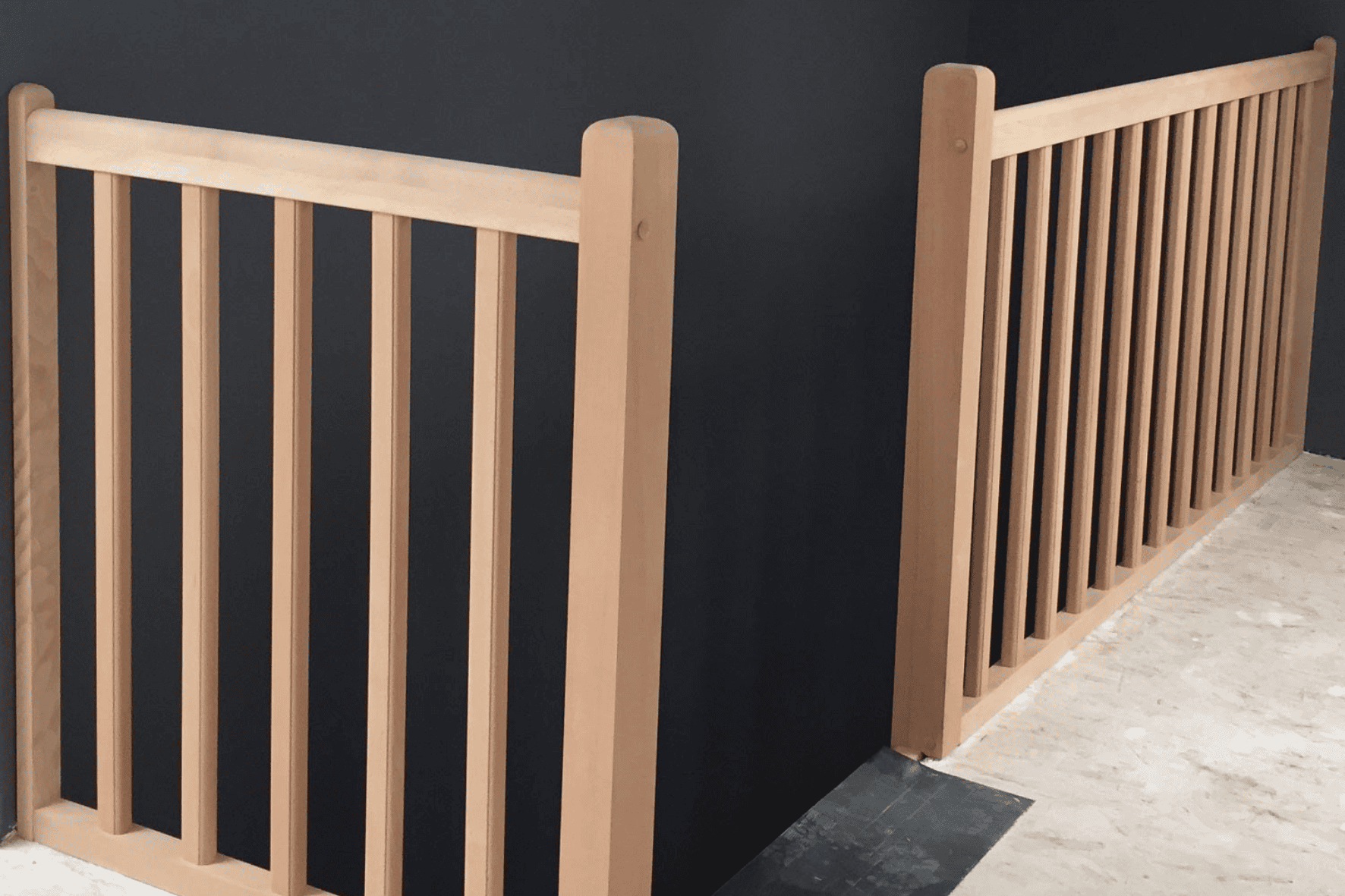 Rambarde à barreaux en bois clair avec balustres verticaux espacés sur une mezzanine.